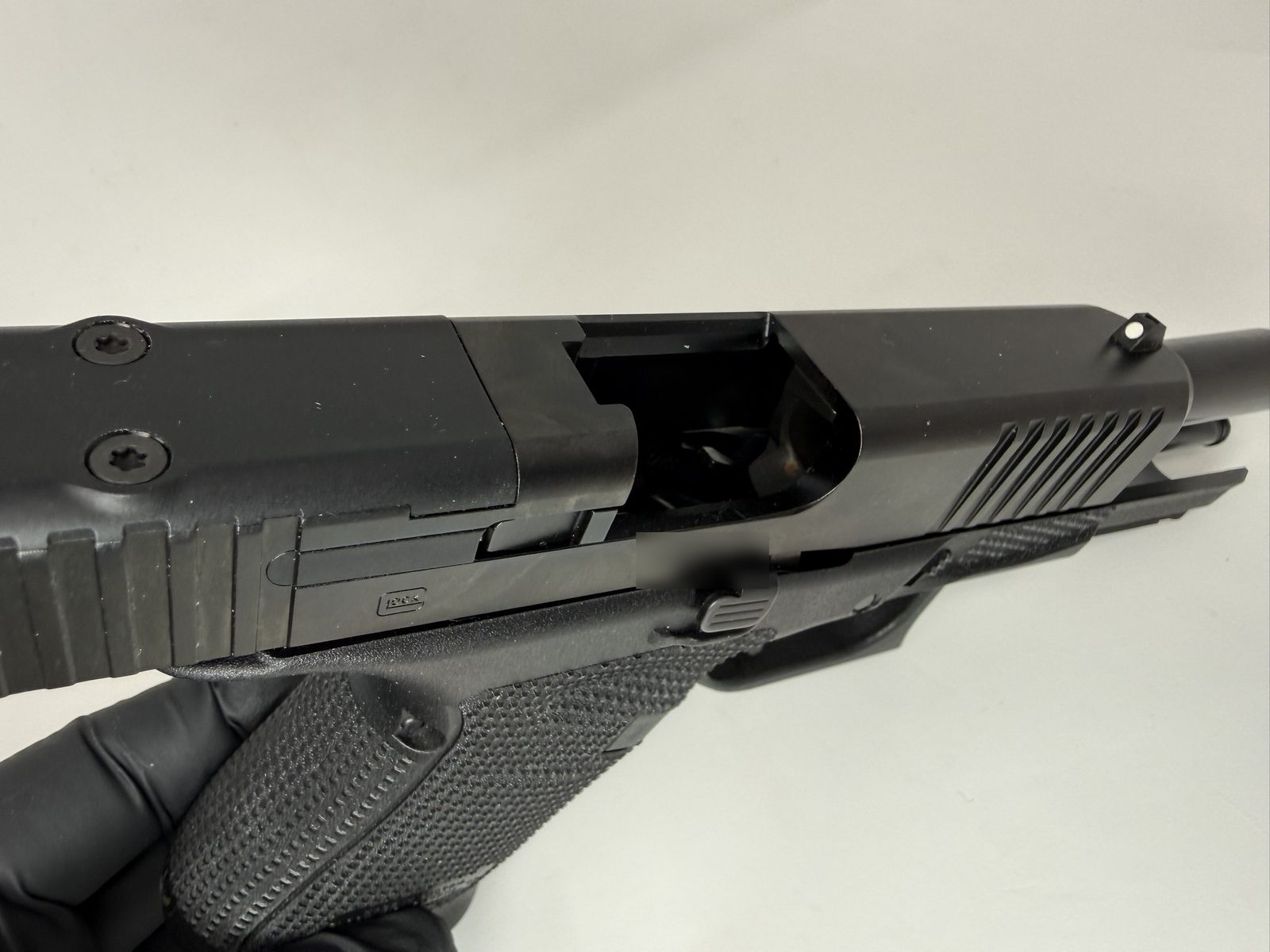 Top view of a Glock pistol with the slide locked back and the ejection port open, showing the chamber area during an unloaded check.