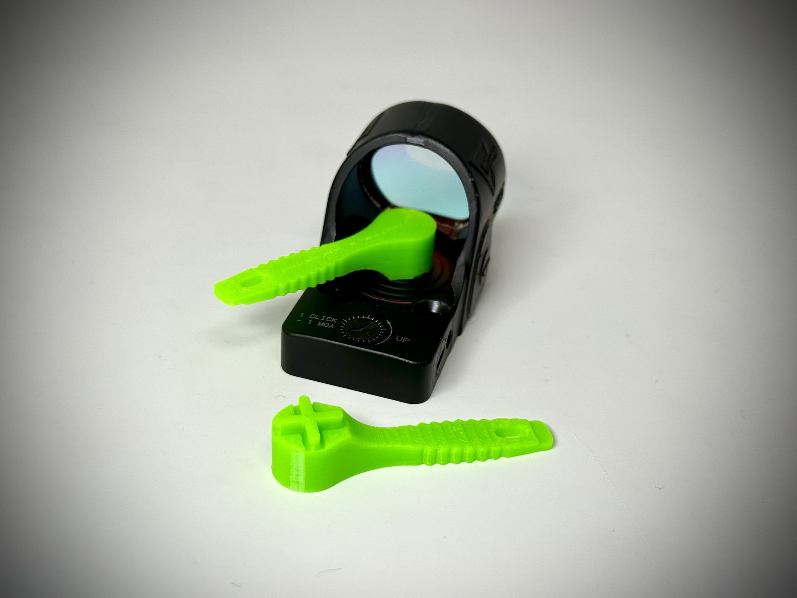 Stonebridge Gunworks SRO Battery Tool V2 in bright green, shown from the side: cross-shaped battery-cap drive at the head, ribbed grip along the handle, and a flat windage adjustment blade at the tail.